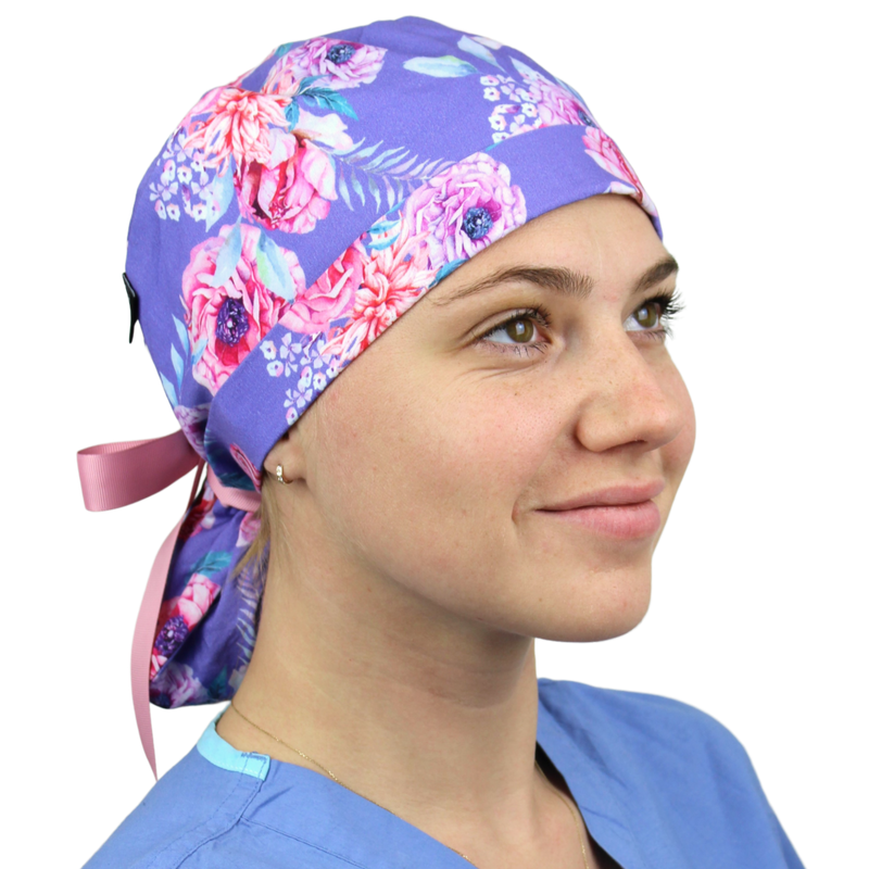 Person wearing a floral-patterned scrub cap and blue scrubs on a white background